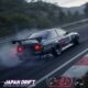 A modified black Japanese racing car is drifting on a track, kicking up smoke. The 