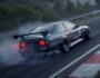 A modified black Japanese racing car is drifting on a track, kicking up smoke. The 
